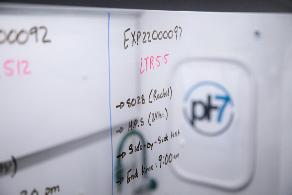 A close-up of a window with Sharpie writing. It features handwritten notes and numbers related to critical metals extraction research.