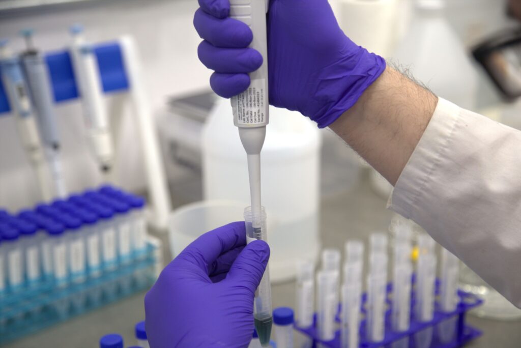 Researcher in lab coat using a pipette to test critical metals.